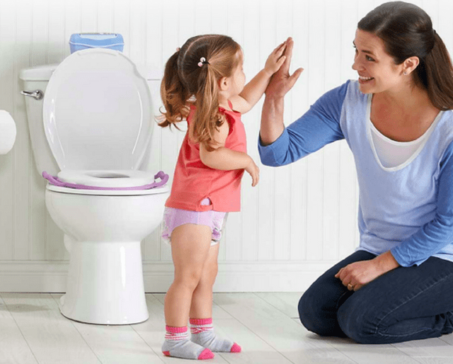 baby standing next to the potty highs five the lady sitting beside her