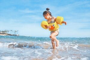 girl wearing inflatable vest running on the shore in the water