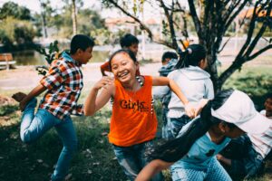 group of children playing outside girl wearing orange t-shirt laughing