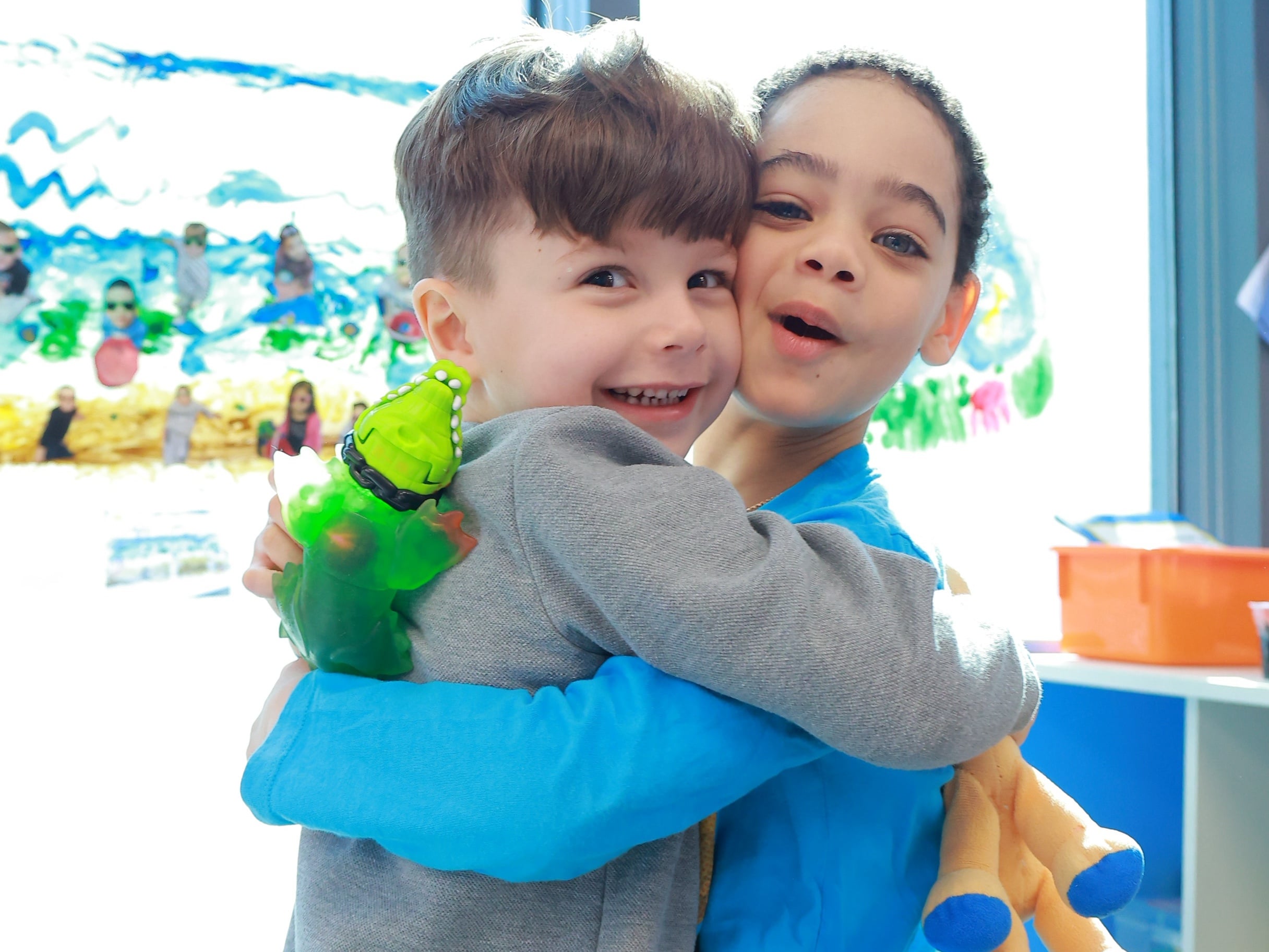 Two young boys hugging each other and sharing toys at Little Scholars Daycare.