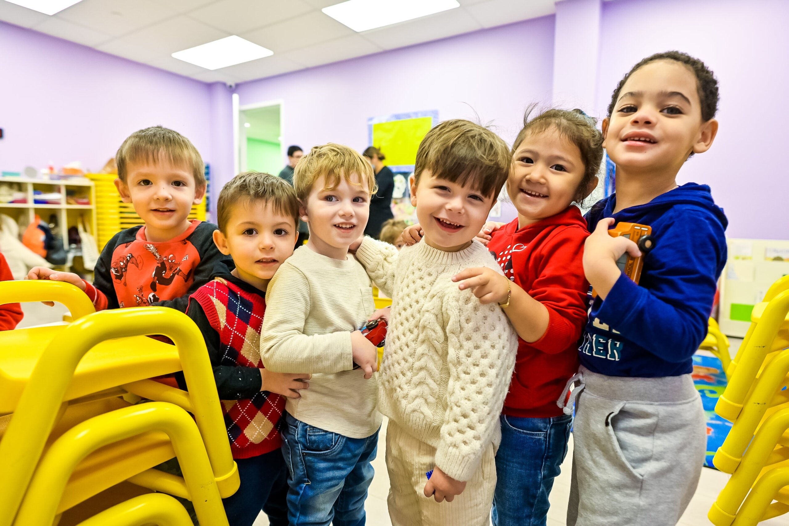 A happy group of children hugging and smiling together at Little Scholars Daycare.