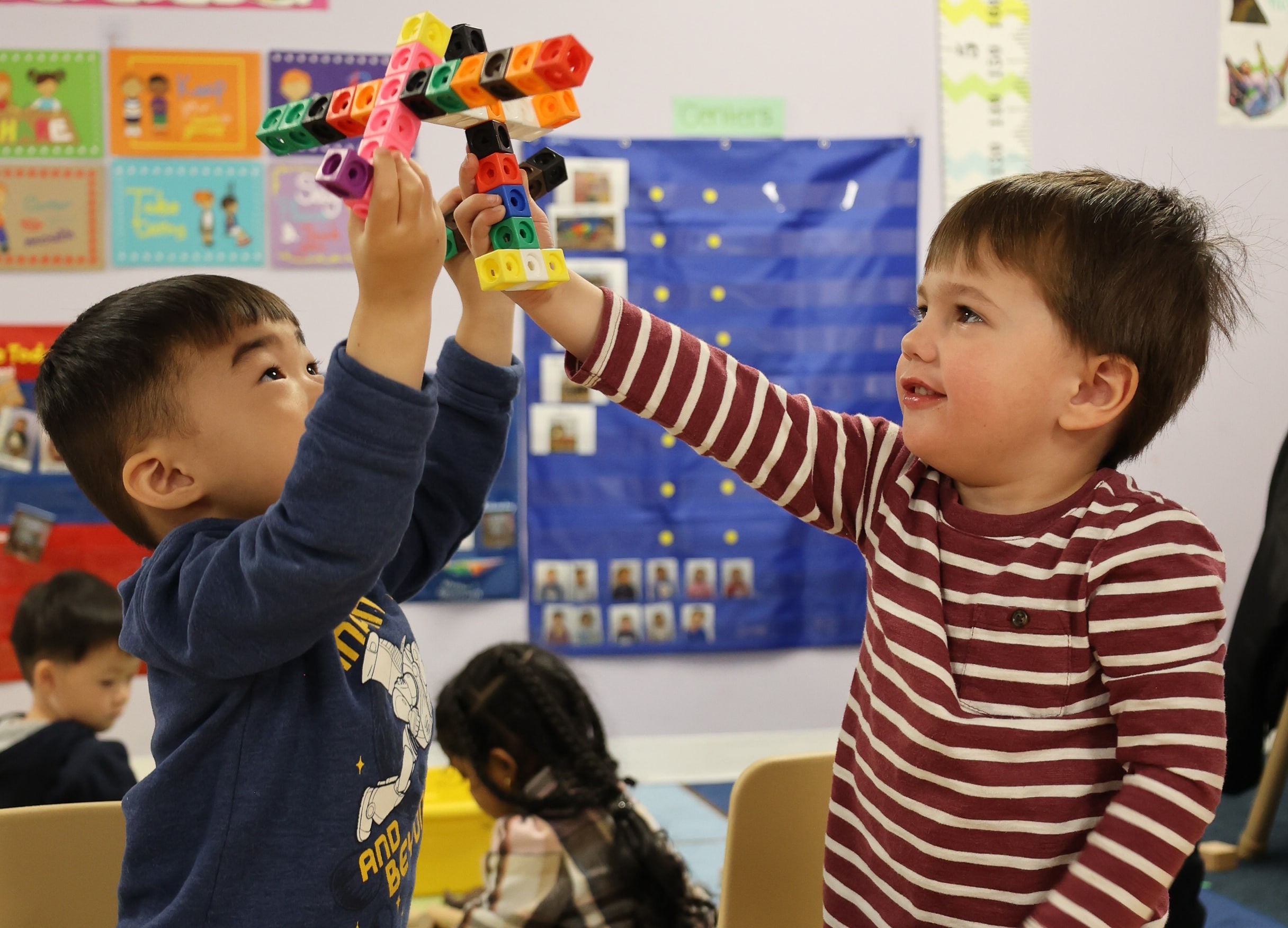 Two children at Little Scholars Daycare collaboratively building with blocks, learning to share and play together.