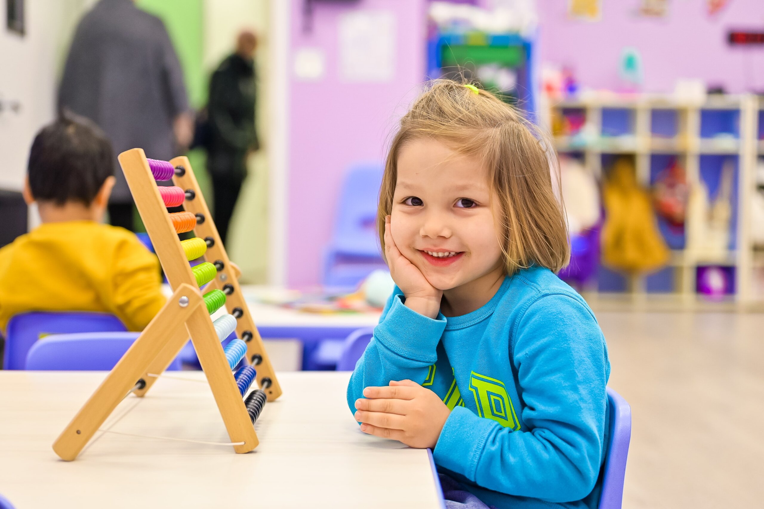 Young girl smiling at Little Scholars Daycare with an abacus in the background.