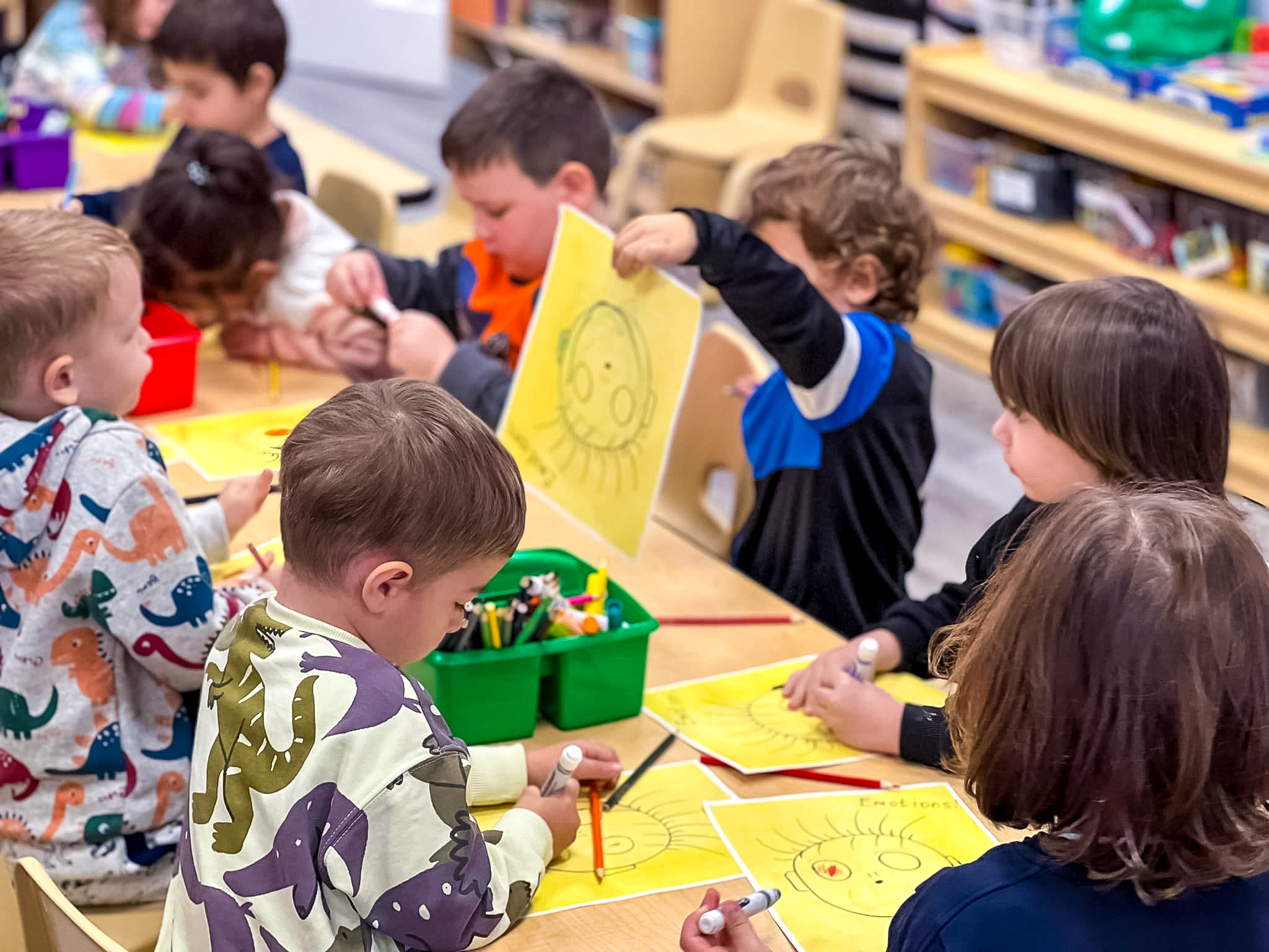 Children sit at the table and play with drawings in the garden Little scholars