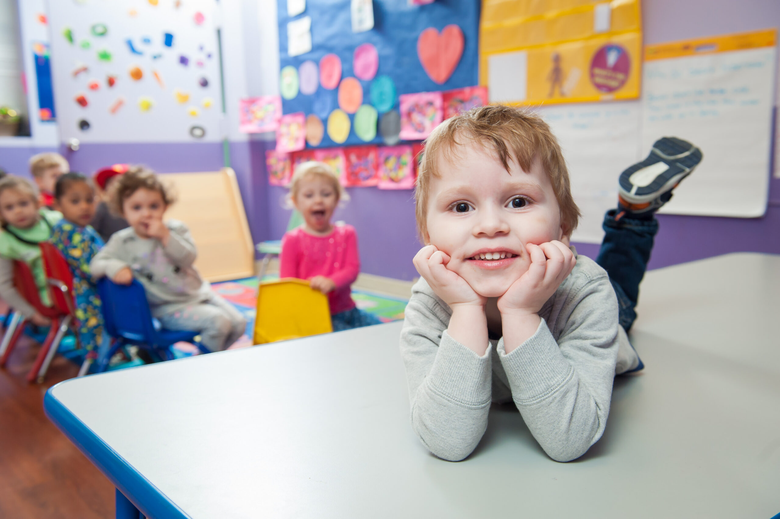 A child in Daycare Little Scholars smiles, other children are in the background