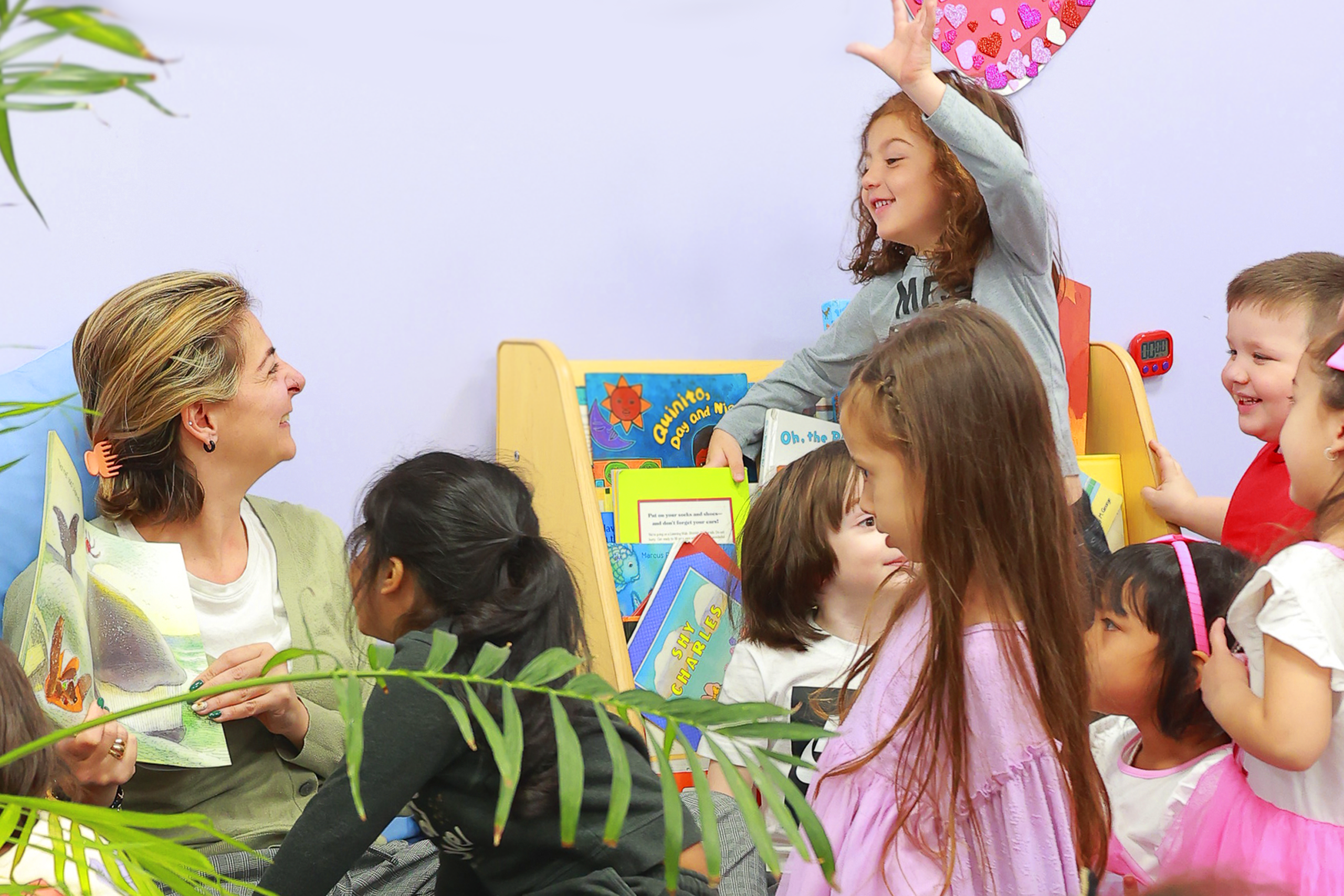 Teacher shows a book near children in Daycare Little Scholars