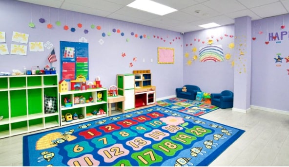 Bright and cheerful daycare classroom with educational toys, colorful number and alphabet rugs, and children's artwork on the walls