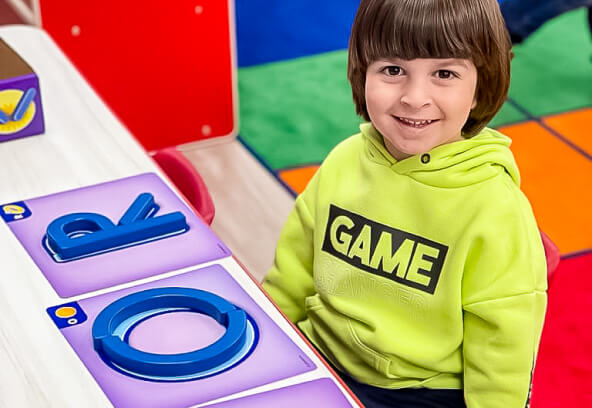 Smiling boy in a game-themed hoodie at Little Scholars Daycare