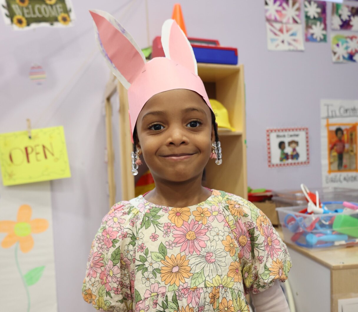 Child at Little Scholars Daycare wearing handmade Easter bunny ears with a bright, joyful smile.