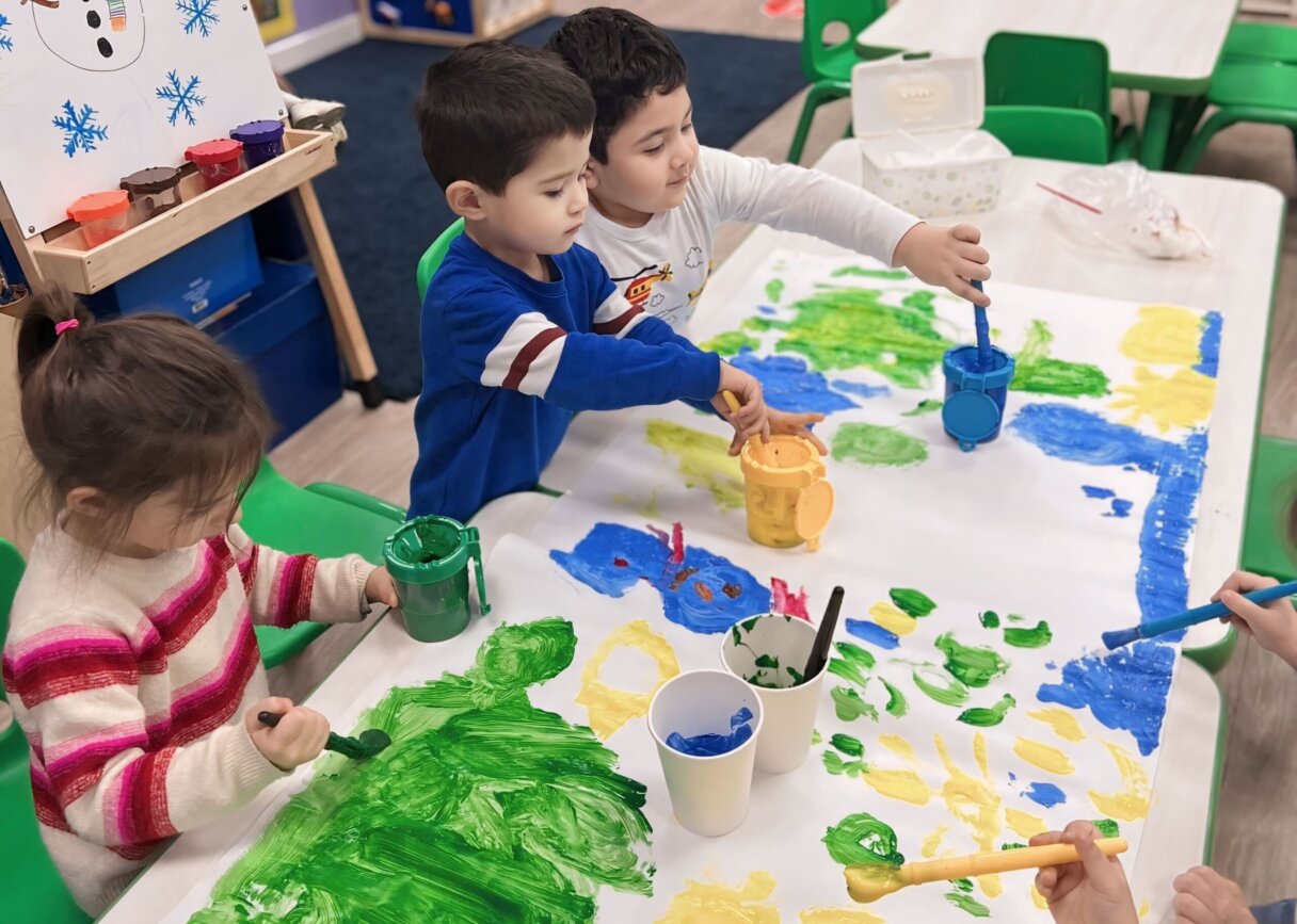 Children collaboratively painting on a large paper in bright colors