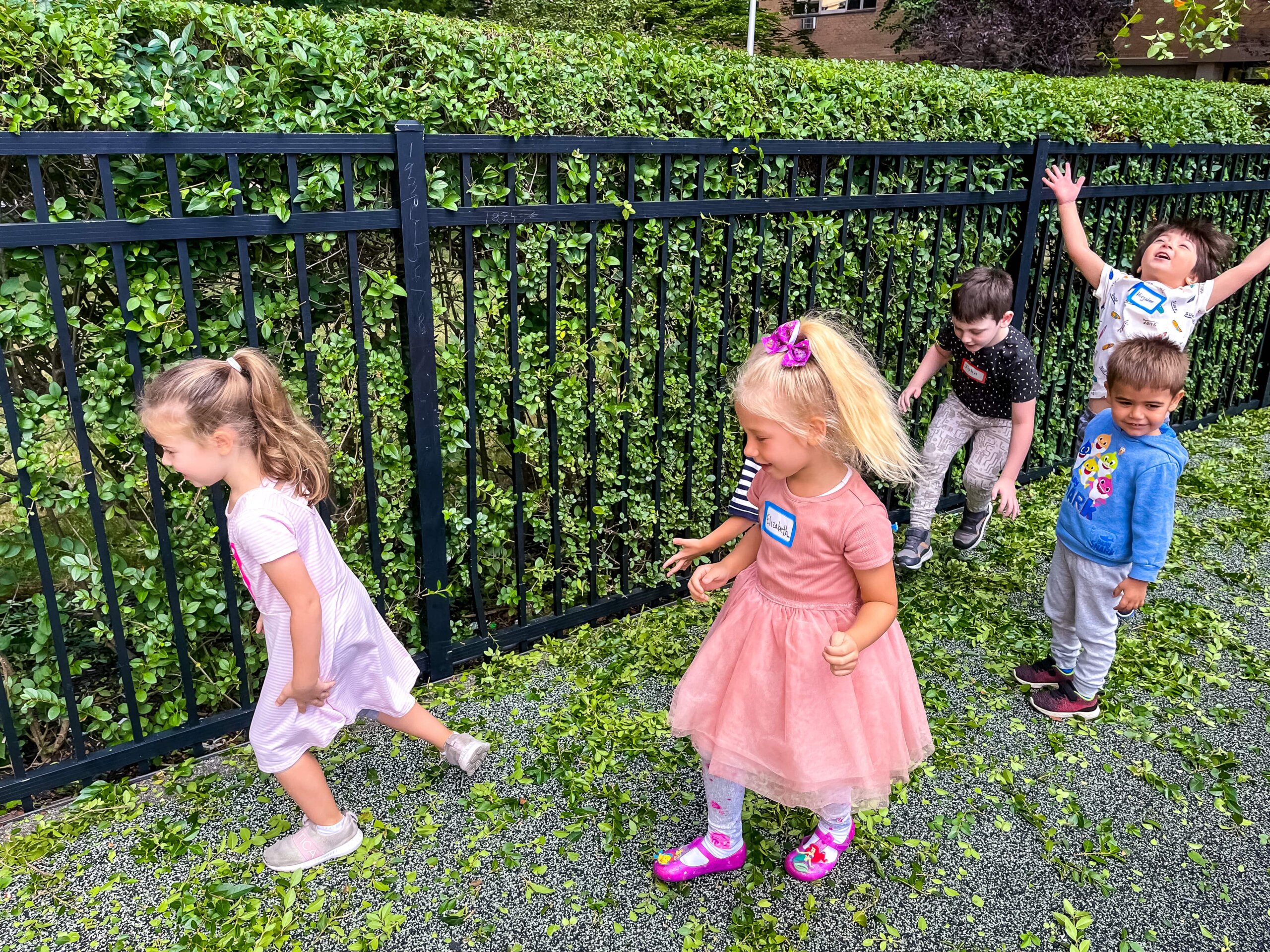 Joyful children playing in a line outside at Little Scholars Daycare during summer.