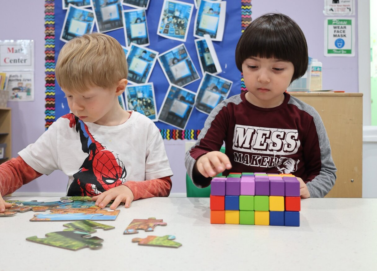 Two young boys engaged in building with colorful blocks and solving puzzles in a classroom