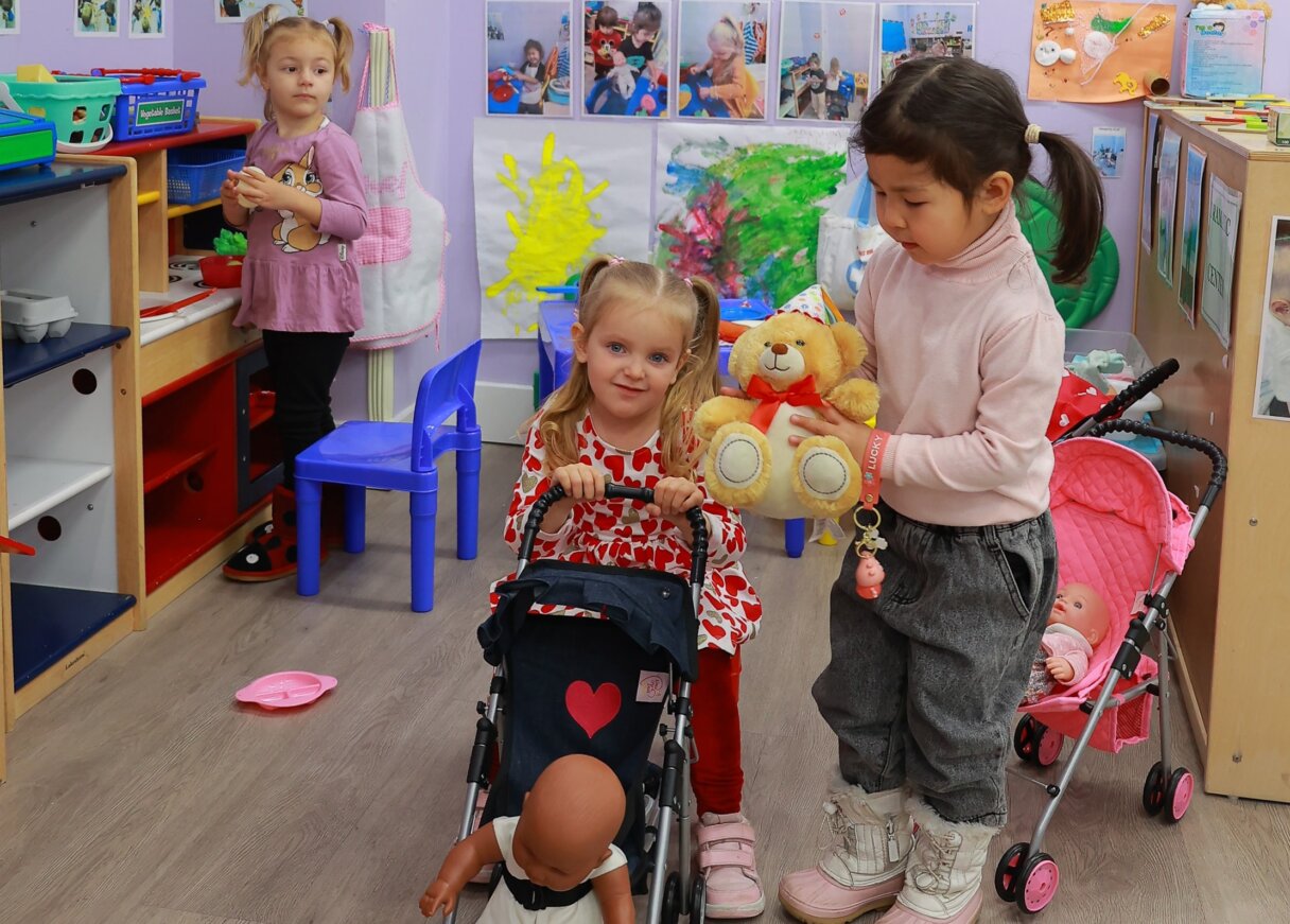 Playful preschoolers organizing toys and dolls in a daycare setting during a spring cleaning activity