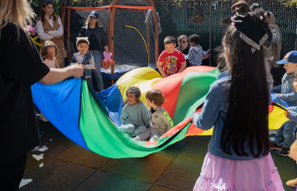 Children at Little Scholars Daycare playing with a colorful parachute during Easter activities.