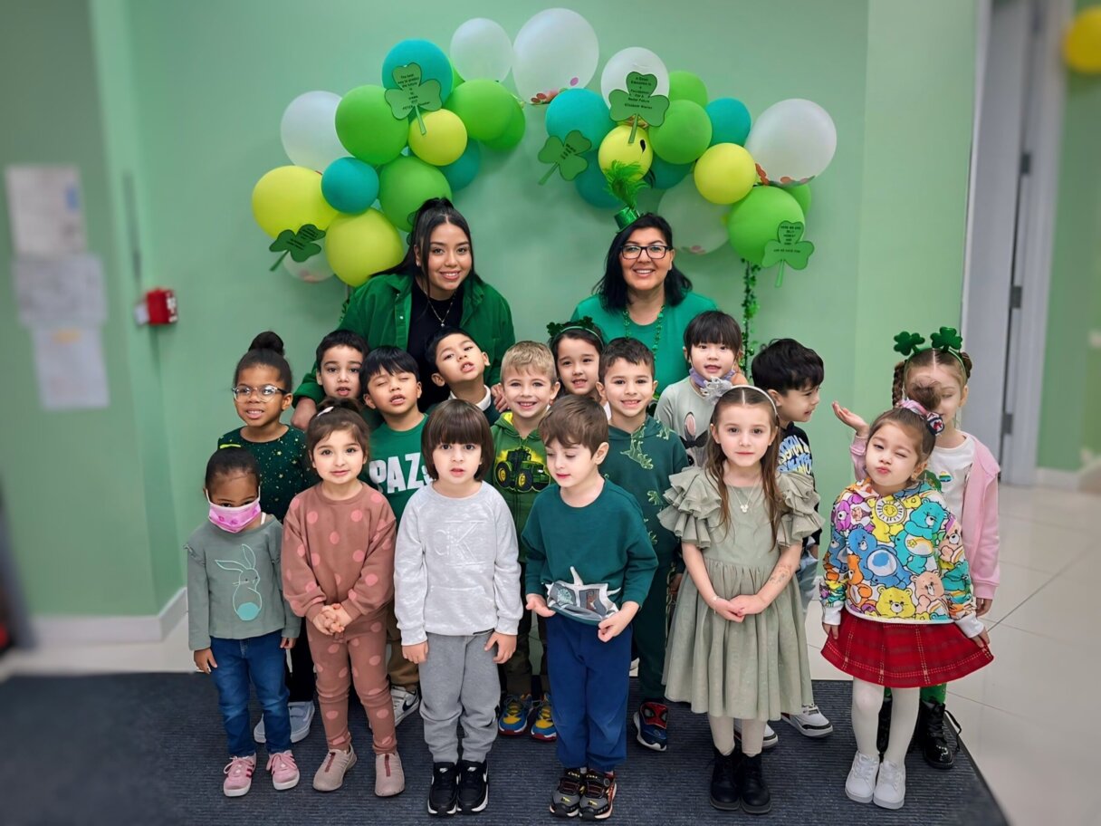 Group of preschool children with teachers wearing green and festive attire for a St. Patrick's Day group photo
