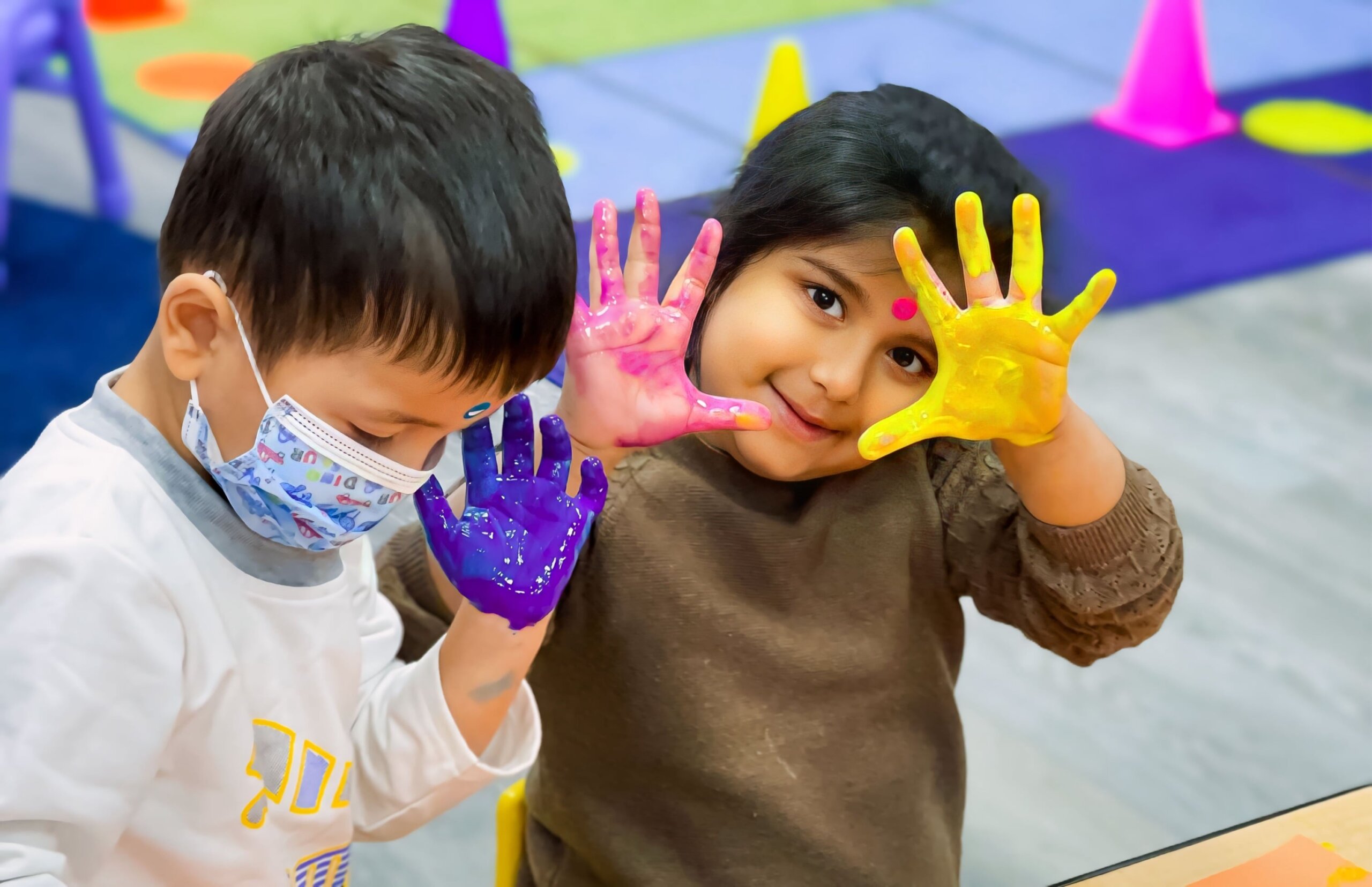 Two kids showing their colorful painted hands during Holi celebrations