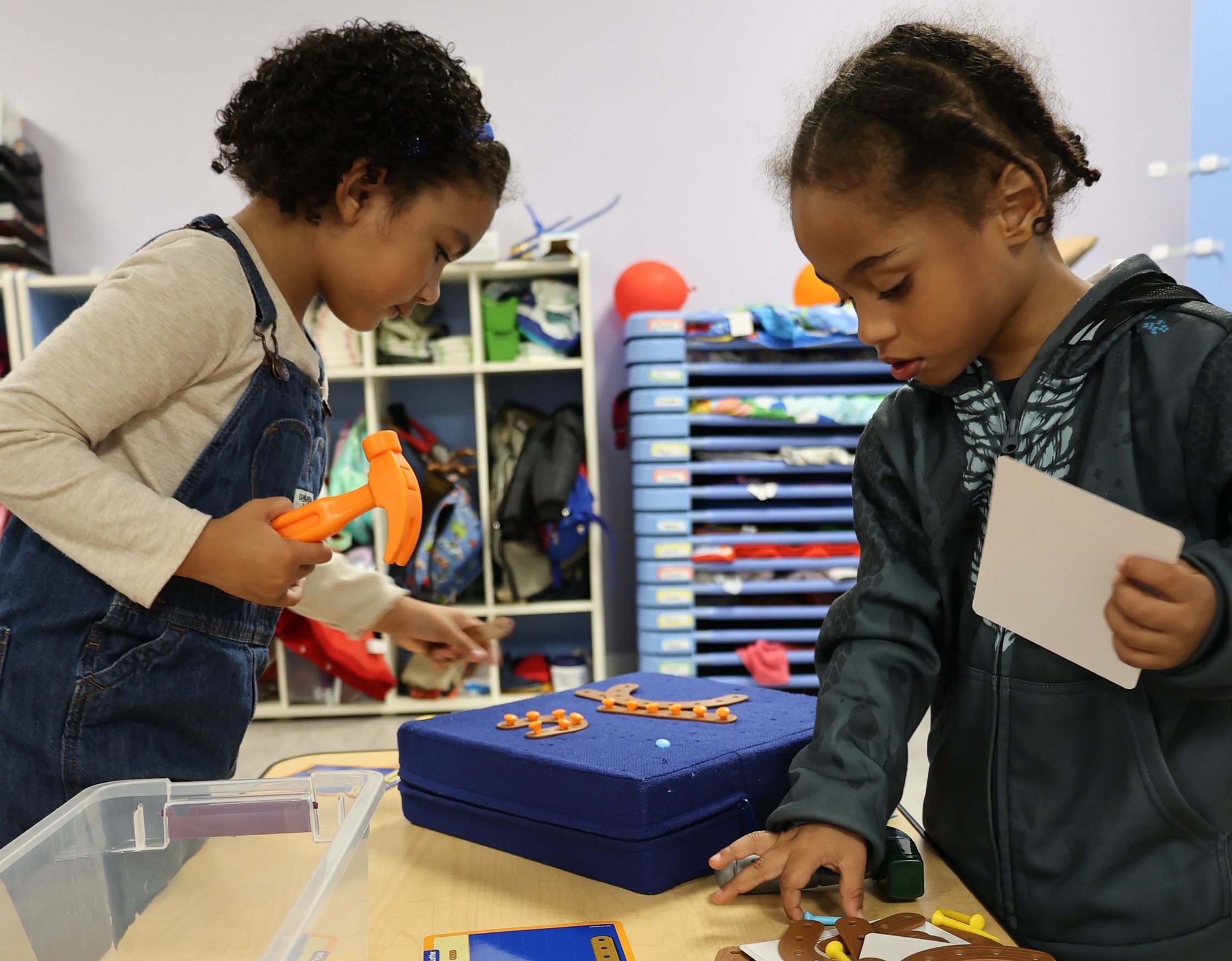 Two children sorting and organizing toys as part of a fun spring cleaning activity in a playroom