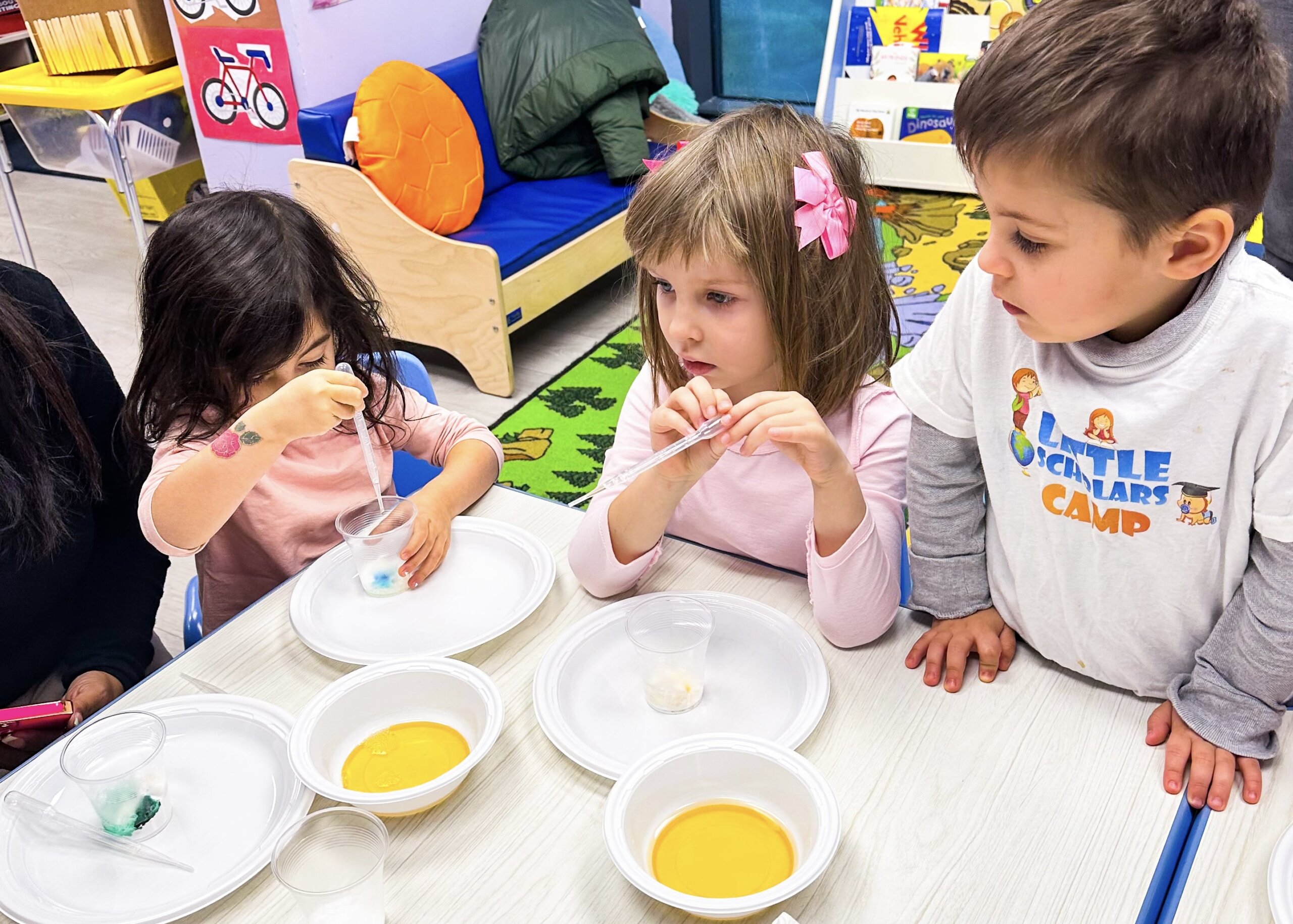 Kids engaged in a DIY science experiment mixing colors in a preschool classroom setting
