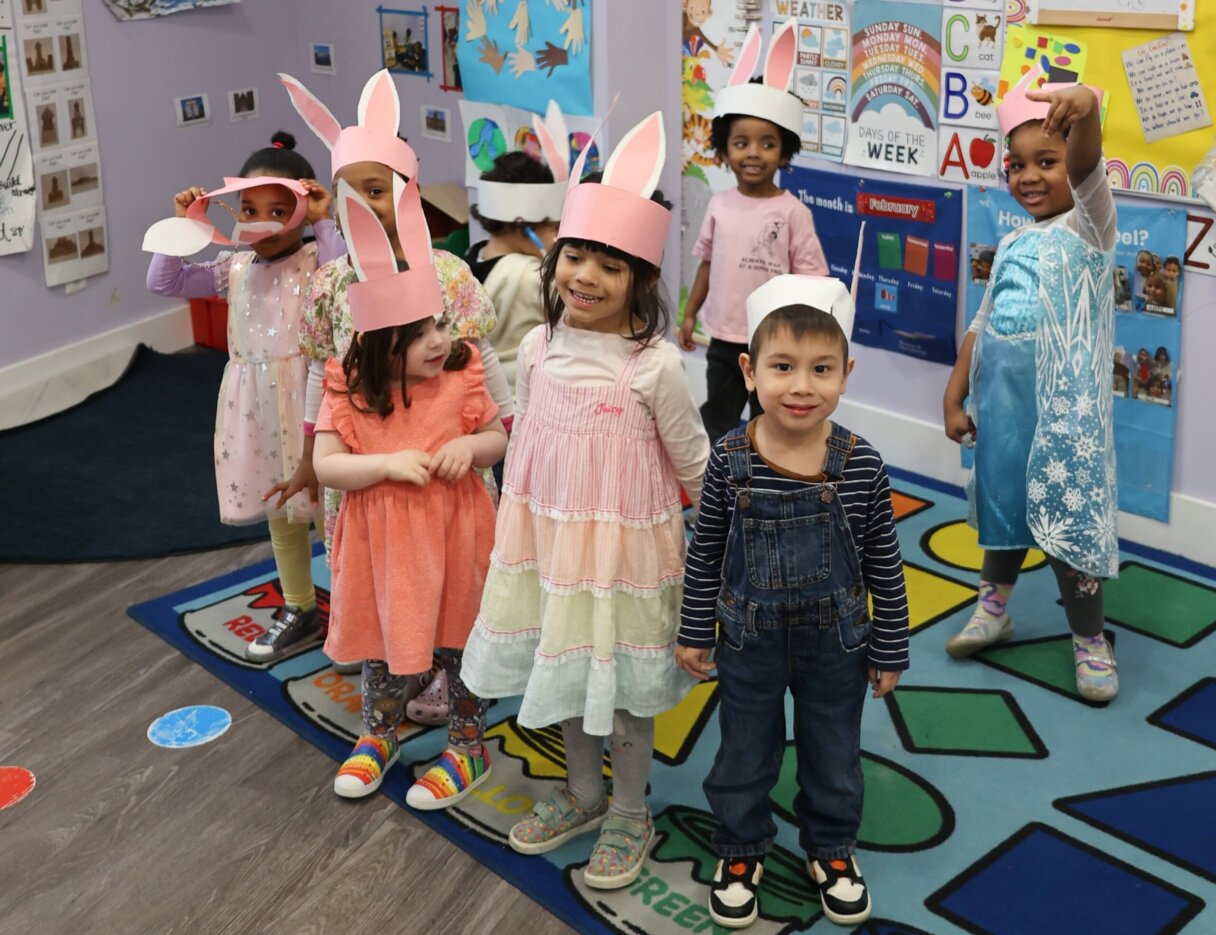 Group of kids at Little Scholars Daycare sporting colorful Easter bunny ears and smiling.