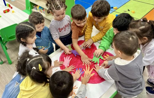 Group of preschool children placing colorful handprints on paper