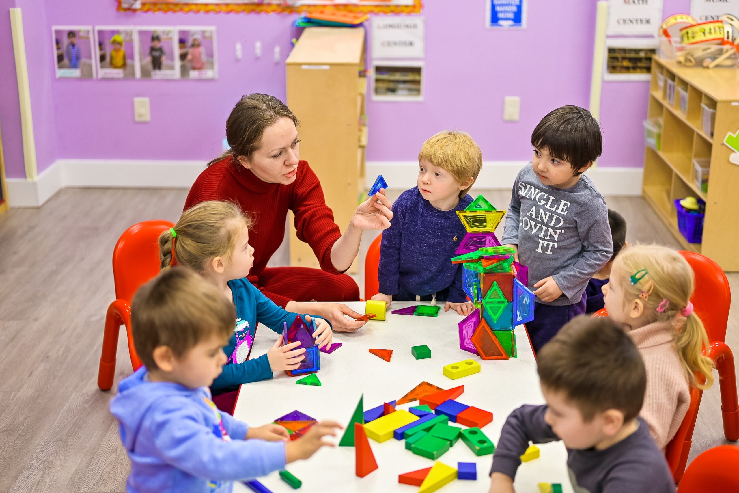 Preschool teacher and children engaging with geometric blocks to build problem-solving skills