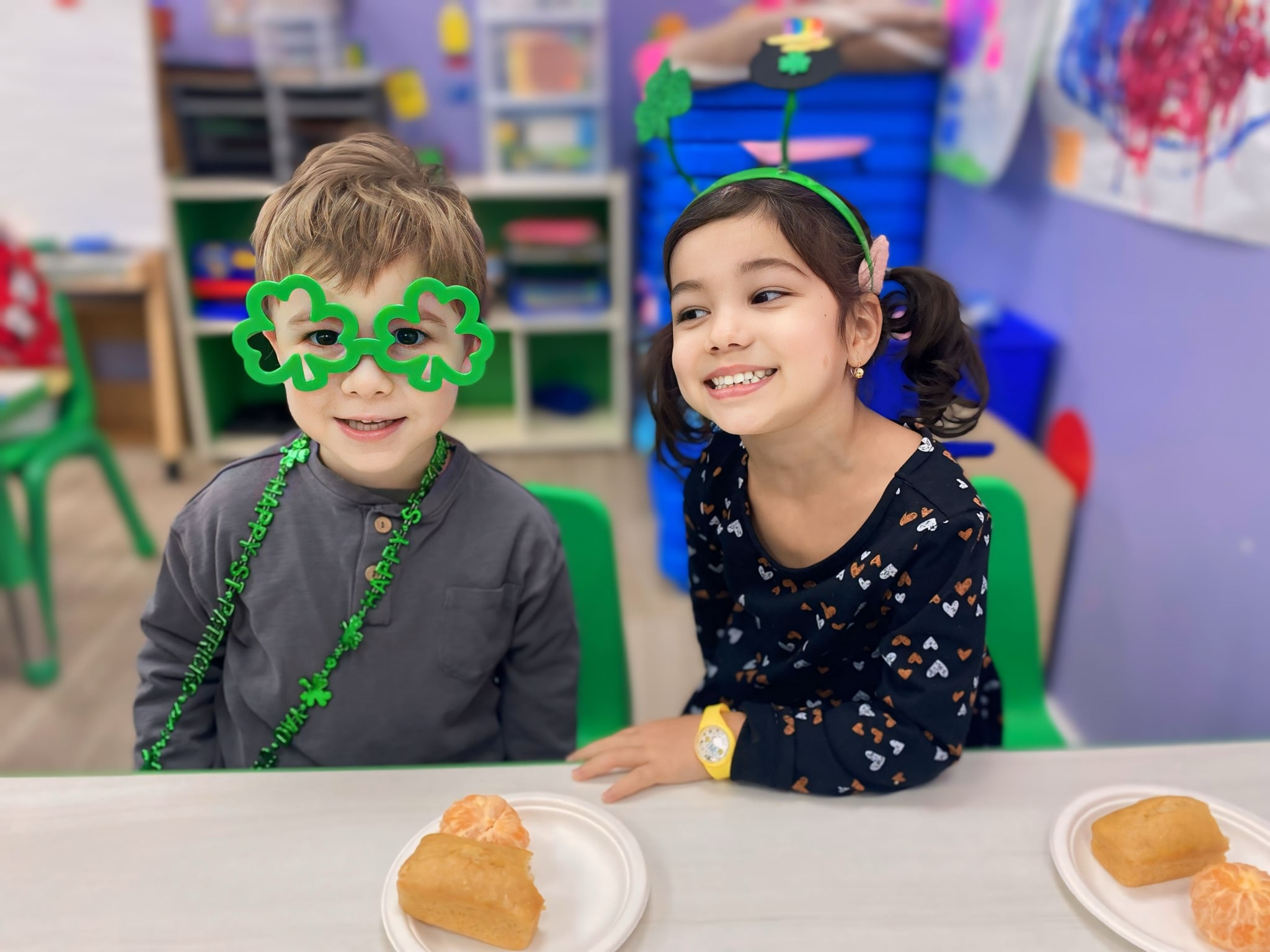 Kids celebrating St. Patrick's Day in the classroom with clover-shaped glasses and festive decorations