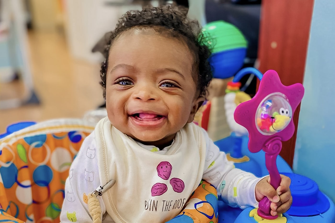 Smiling baby playing with a musical toy rattle