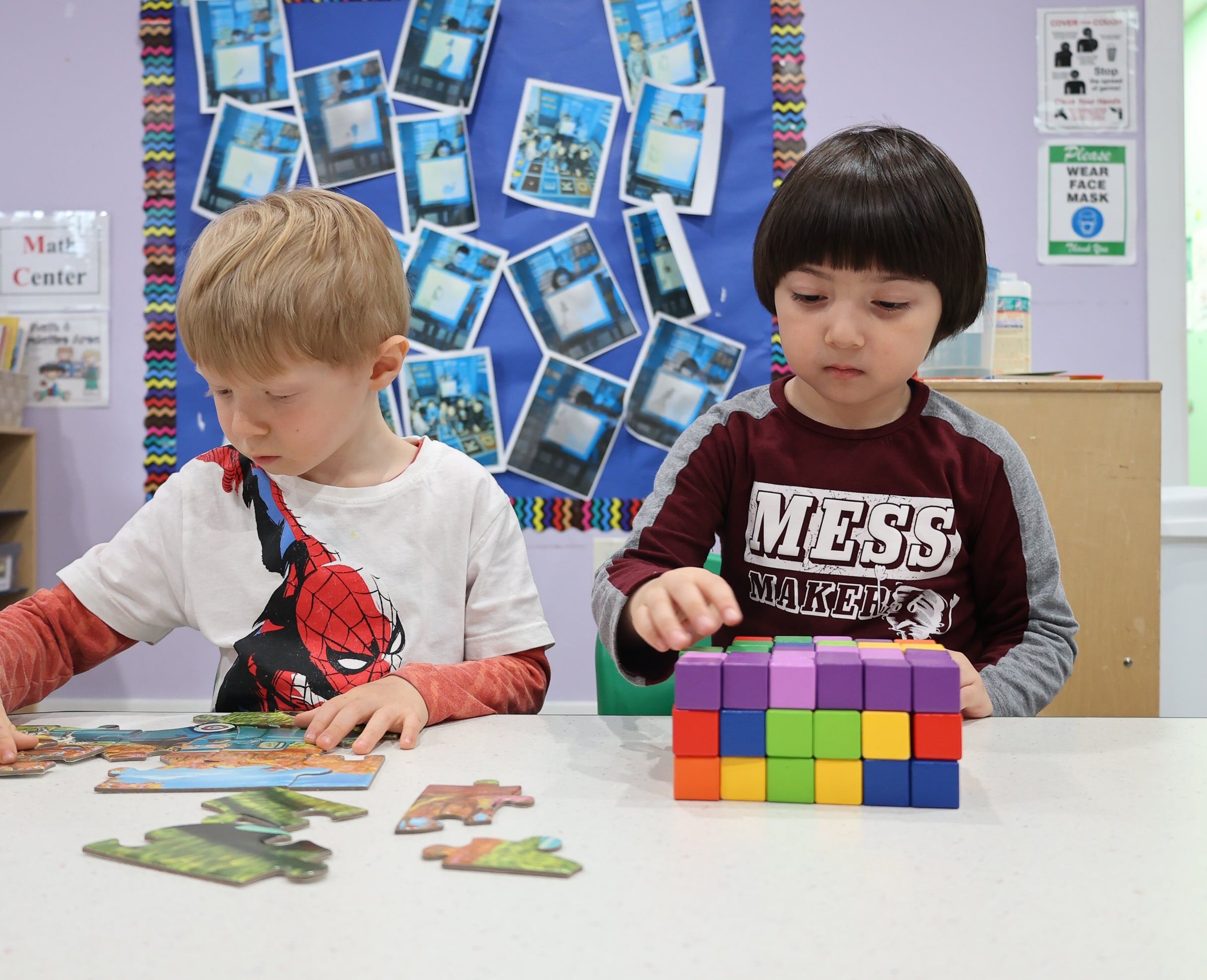 Two children at daycare focusing on assembling a puzzle and building with colorful blocks
