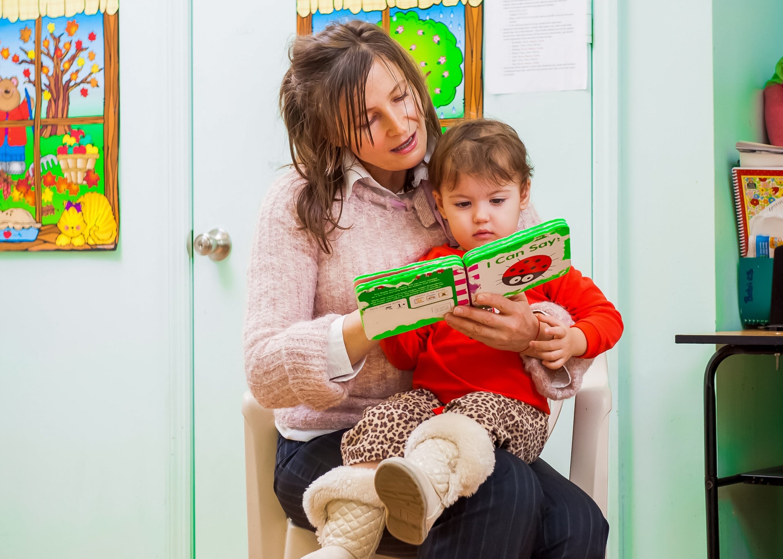 A Little Scholars educator reading a book with a child, highlighting the importance of early literacy.