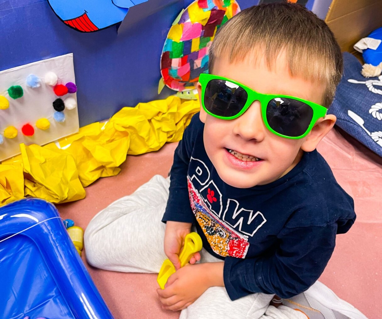 Joyful child wearing bright green sunglasses at Little Scholars Daycare.