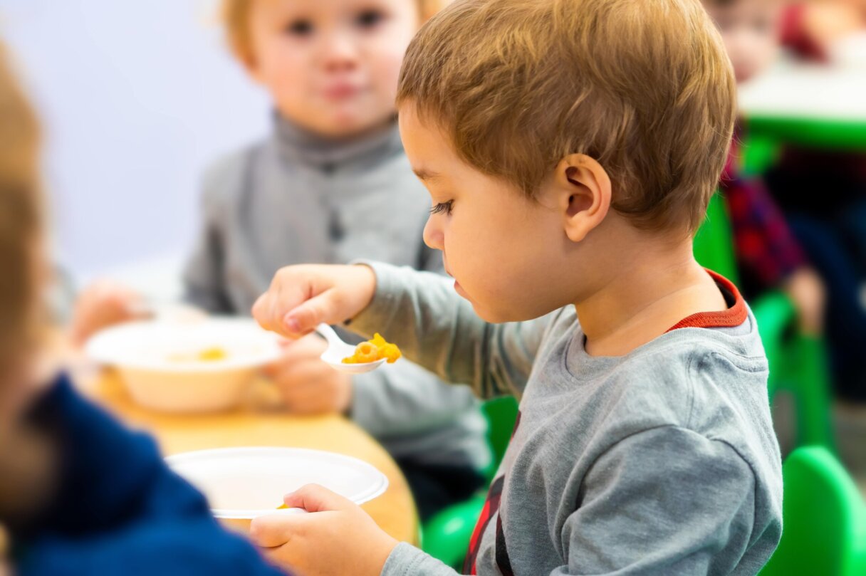 Toddler focused on eating a healthy meal at Little Scholars Daycare